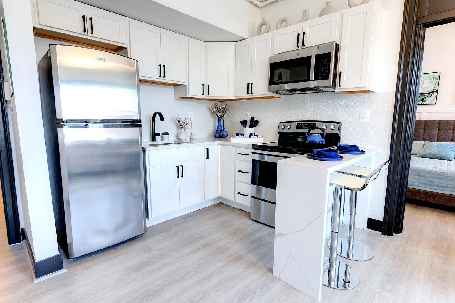 A modern kitchen with a stainless steel refrigerator and white cabinets.